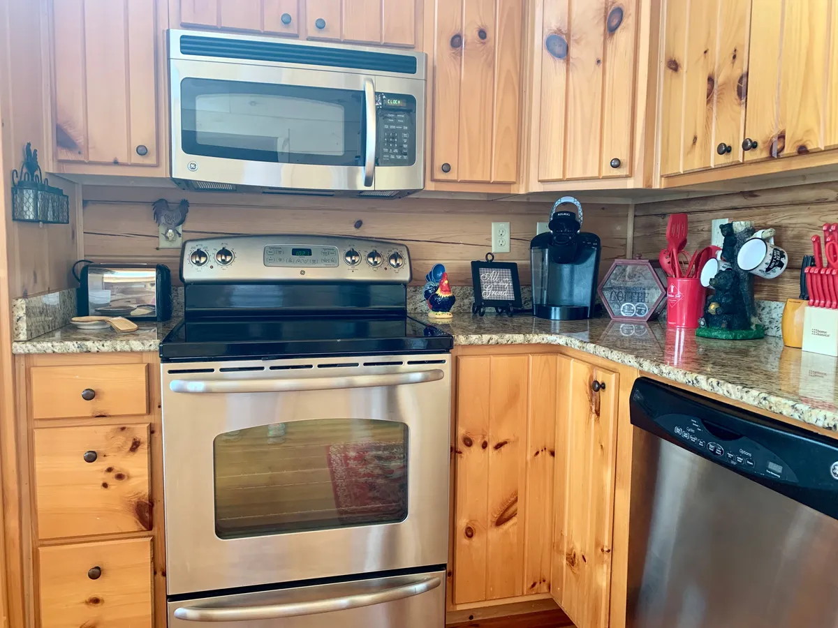 A chef-ready kitchen featuring stainless steel appliances, granite countertops, wooden cabinetry, and an array of kitchen gadgets and decor. The inviting setup is ideal for both cooking and entertaining guests, complementing gatherings in the great room.
